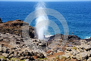 Tourists admiring the Nakalele blowhole on the Maui coastline. A jet of water and air is violently forced out through the hole in