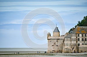 Tourists on the beach and one of the towers of the wall of Mont Saint Michel, France