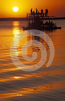 Tourists on a boat at sunset, Botswana.