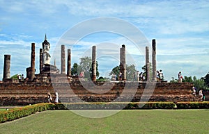 Tourists and Buddha in Wat Mahathat or Mahathat Temple in Sukhothai Historical Park in Thailand. The temple`s name translates to `