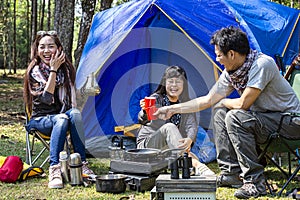 Tourists are camping in the forest. Group of adventure tourist camping enjoy and happy in coffee time with guitar playing together