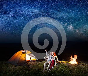Tourists in camping at night against starry sky