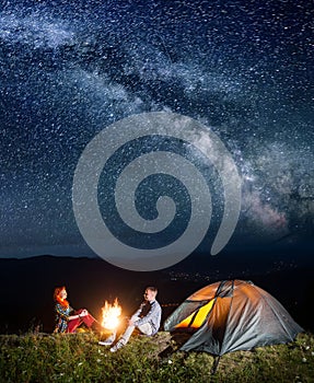 Tourists in camping at night against starry sky