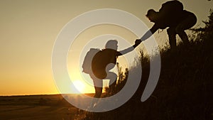 Tourists climb the mountain at sunset, holding hands. teamwork of business people. Traveler man holds out a woman`s hand photo