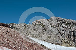 Tourists and Climbers Walking in Stone Path among Barren Mountains in Italian Dolomites Alps in Summer Time