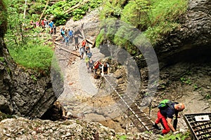 Tourists climbing iron ladders in Slovak Paradise