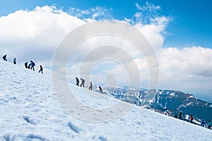 Tourists climbs for camping to the snow-capped mountain top. Con