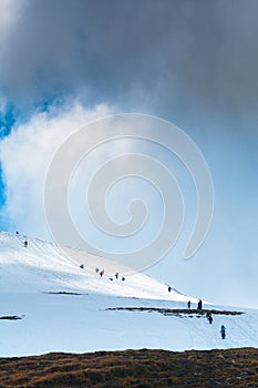 Tourists climbs for camping to the snow-capped mountain top. Con