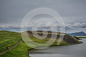 Tourists on the coastline around the pond Stakholstjorn with pseudo craters - natural monument near Lake Myvatn in Northern