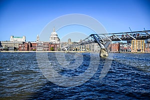 Tourists crossing the River Thames by walking through Millennium Bridge with Saint Paul`s Cathedral in background, London, UK