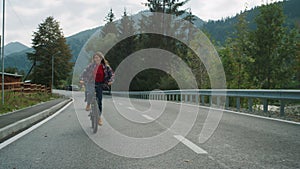 Tourists enjoy biking outdoors on forest road. Couple looking around mountains.