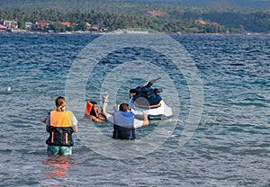 Tourists enjoy driving jet ski on the ocean. A young couple boardes a jetbike photo