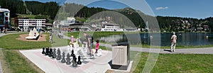 Tourists enjoy summer activities on the lakeshore in Arosa with the train and cable railway station in the background