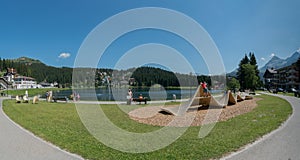 Tourists enjoy summer activities on the lakeshore in Arosa with the train and cable railway station in the background