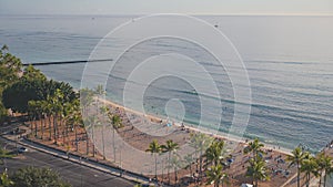 Tourists enjoy the warm sun on a tropical beach. Amazing sunset at Waikiki beach. Hawaiian Island Oahu. Biruse waves of