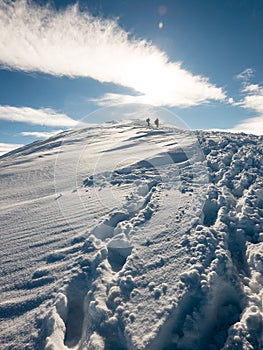 Tourists enjoying high mountains in snow on a sunny day