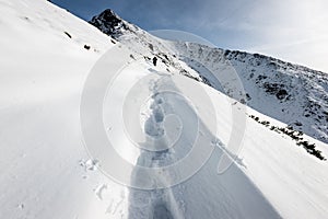 Turisti, ktorí si užívajú vysoké hory v snehu za slnečného dňa