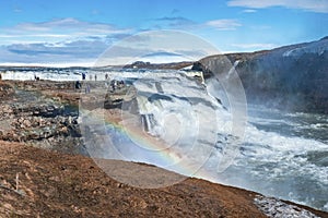 Tourists enjoying view of Gullfoss waterfall in Golden Circle against blue sky