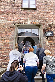 Tourists entering with guild in Auschwitz concentration camp complex museum