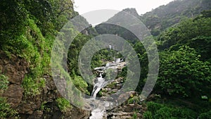 Tourists explore Ravana Falls Sri Lanka, plants surrounds cascading water. Visitors at popular travel destination enjoy