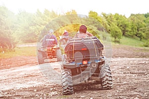 Tourists on a few quad bikes ride on rough terrain on a sunny day in the spring. Toned photo