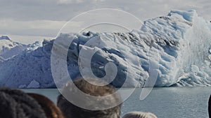 Tourists Gaze at Majestic Iceberg from a Navigating Boat