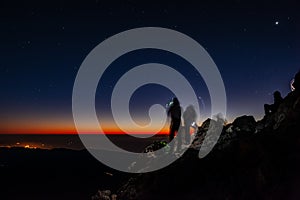 Tourists with headlamps at dawn waiting for sunrise at Pico del Teide mountain in El Teide National park. Tenerife, Canary Islands