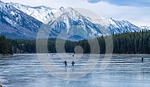 Tourists here doing ice-skating in Johnson Lake in winter. Banff National Park, Canadian Rockies.