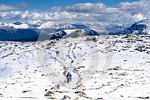 Tourists hike along a snow covered mountain top trail