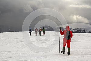 Tourists hikers in winter snow covered mountains and dramatic cl