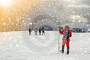 Tourists hikers in winter snow covered mountains and dramatic cl