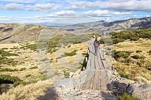 Tourists hiking on wooden trail to the Laguna Grande de Gredos lake, Spain. photo