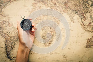 Tourists hold a compass and locate a place on a world map.