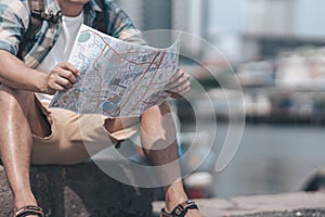 Tourists hold maps to find attractions, restaurants or hotels while waiting for their bus or passenger boat and the background is