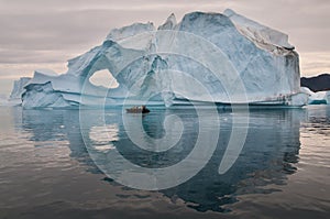 Tourists in Inflatable Rubber Boat in front of weathered iceberg, Scoresby Sund, Greenland photo