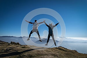 Tourists jumping energetically and happily at the top of the mountain