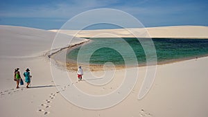 Tourists, lagoon and dunes at Lencois Maranhenses National Park, Maranhao, Brazil