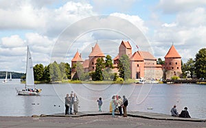 Tourists on the lake coast with Trakai Castle, Lithuania