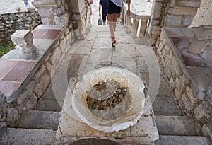 Tourists leave in stone bowl lucky coins in the church to wishes