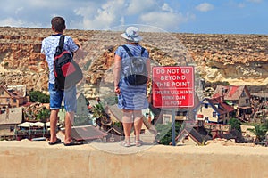 Tourists in Malta stands on dangerous cliff edge - Near sign DO NOT GO BEYOND THIS POINT - TMURX LILL\'HINN MINN DAN IL-POST