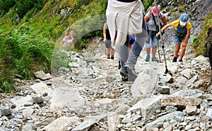 Tourists on the mountain trail as a concept of crowds going on trips in the summer. Lots of people in the season on the trails in