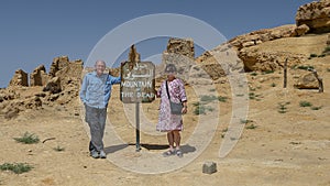 Tourists with painted steel sign for Gebel Al Mawta, the `Mountain of the Dead`, in Siwa Oasis, Egypt.