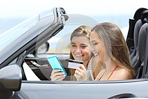 Tourists paying online inside a rental car on vacation