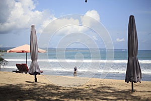 Tourists playing at the sea framed on Closed Beach Umbrellas in Kuta Beach Bali Island, Indonesia photo