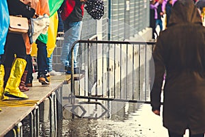 Tourists in rain coats and rain boots walking on raised walkways during flooding in Venice, Italy