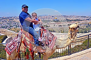 Tourists ride a camel against the old city of Jerusalem, Israel.