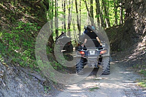 Tourists ride a quad bike along a forest road