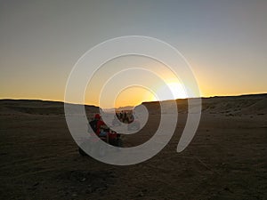 Tourists ride on a quad bike in the desert at sunset