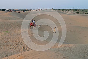 Tourists riding camels, Camelus dromedarius, at sand dunes of Thar desert, Rajasthan, India. Camel riding is a favourite activity