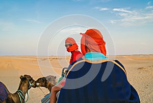 Tourists in the Sahara desert on camels. The entertainment of tourists.